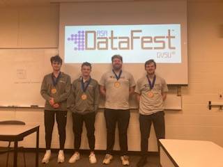 Four students awarded the Best Insight Award pose in front of the DataFest logo.